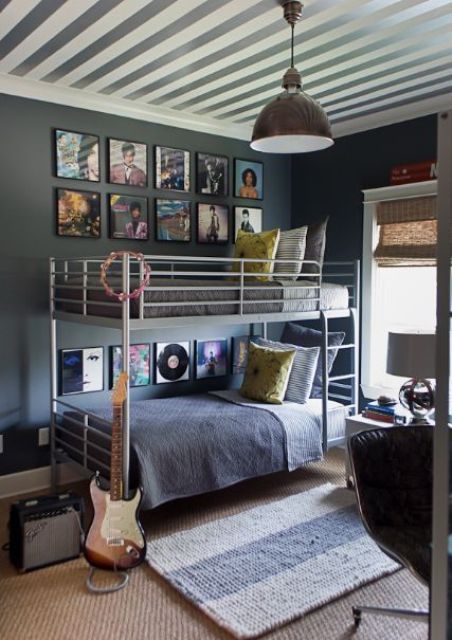 a modern shared teen boy bedroom with a metal bunk bed, a striped ceiling, a leather chair and a gallery wall