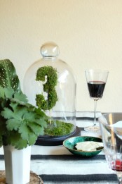 a moss table number on a stick placed in a cloche is a cool spring idea for special event decor