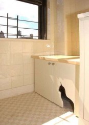 a neutral cabinet with a cat cutout for entrance and a cat litter box inside is a stylish and simple solution