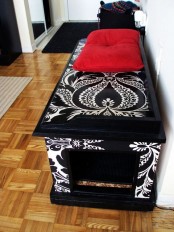 a stenciled black and white storage bench with a cat litter box inside and an entrance on one side