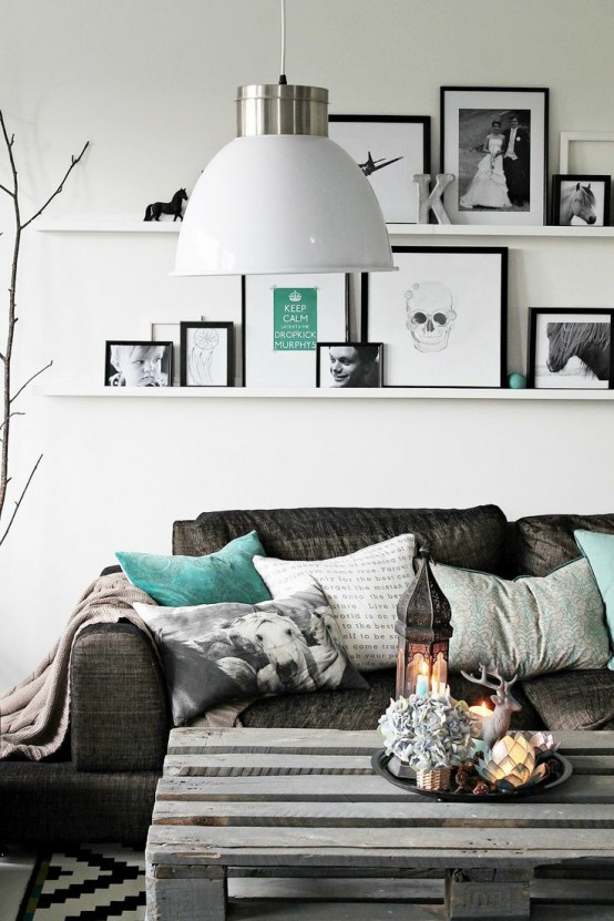 a monochromatic living room with dark and whitewashed furniture, ledges with black and white artworks and figurines and lanterns and pendant lamps