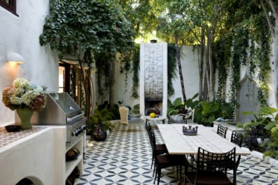 a modern terrace with a mosaic black and white floor, a fireplace, a dining set with black chairs and a mini outdoor kitchen