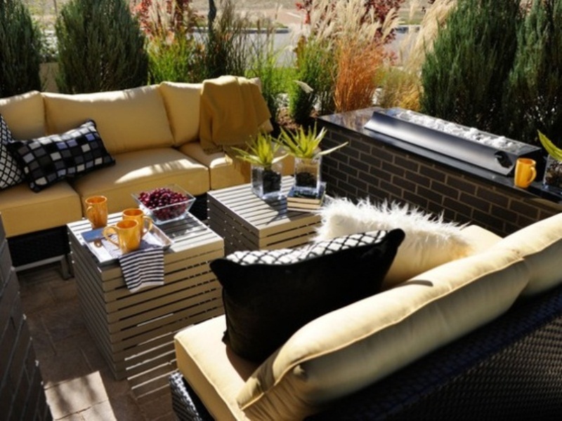 A small modenr rooftop terrace with comfy yellow sofas, crate tables and a drink cooler by the side is a dream