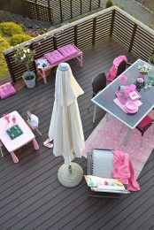 a modern blacony terrace with simple furniture, a kids’ drawing nook, bright pink touches and a potted plant for a fresh feel