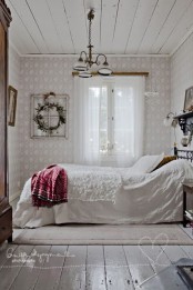 fur and plaid blankets and a greenery wreath make this all-white bedroom very welcoming and very winter-like