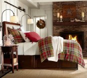 plaid and red bedding and a holiday wreath plus lights give a cozy wintry feel to the bedroom