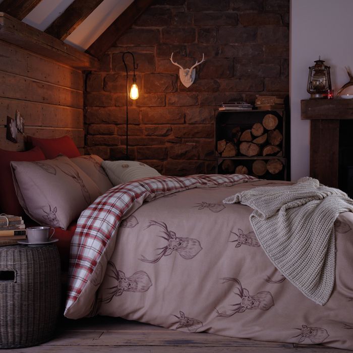 Mauve and plaid bedding with deer prints, a knit blanket and some firewood in crates make the bedroom winter ready and cozy