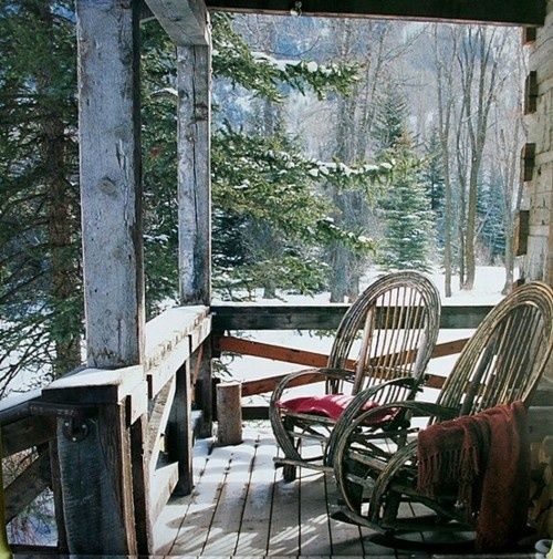 a rustic winter terrace with wicker chairs and burgundy blankets, with a forest view is a lovely space to spend time