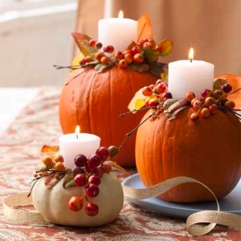 Pillar candles in pumpkins with berries and leaves are very bright, cozy and fall like