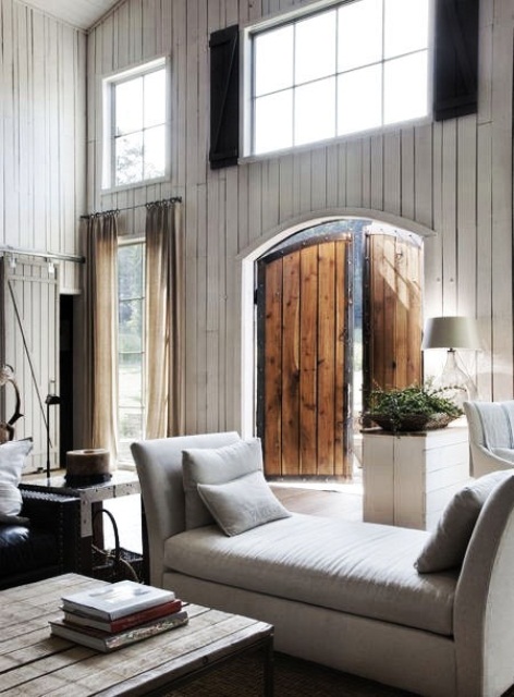 a relaxed barn living room with white planked walls, elegant white seating furniture, a low planked wooden table and neutral textiles is amazing