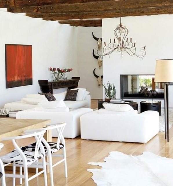 A pretty barn inspired modern living room with a double sided fireplace, white seating furniture, a dark console and dark tables for a contrast
