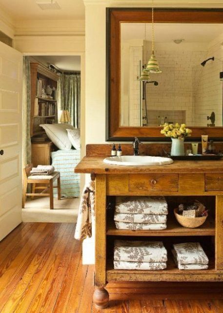 A chic farmhouse bathroom with much rich stained wood in decor, a large vintage vanity and a large mirror