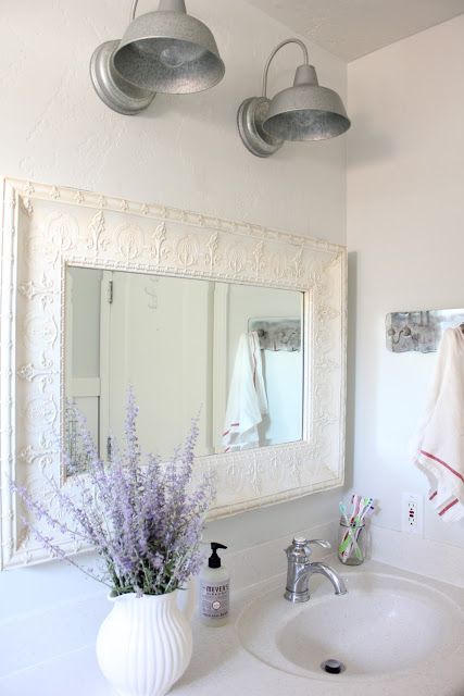 an elegant white farmhouse vanity and a vintage mirror frame plus some lavender in a vase