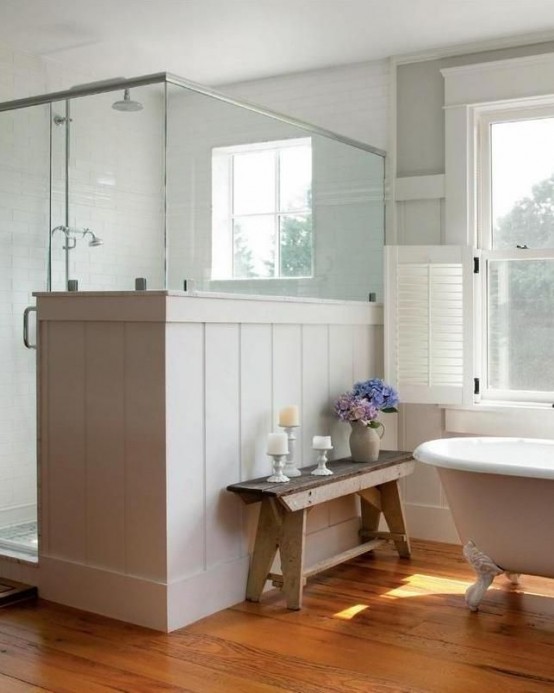 a cozy and light-filled neutral farmhouse bathroom with a clawfoot bathtub, a shower partly clad with beadboard