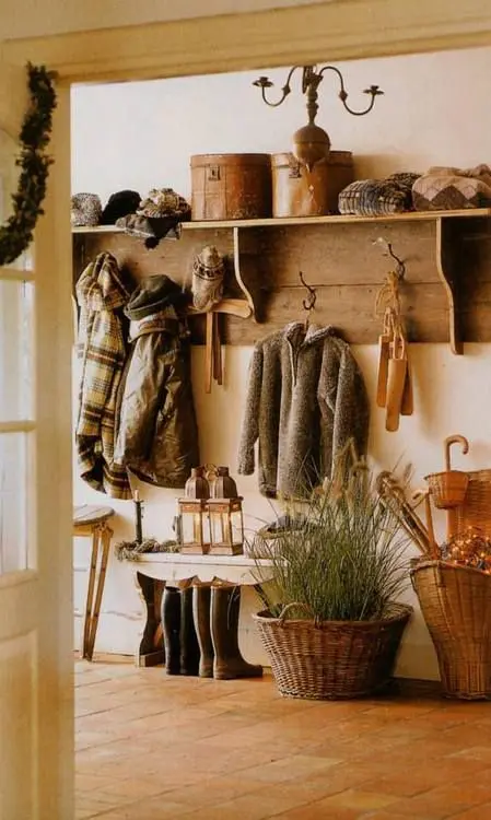 a cozy rustic entryway with a large wooden rack, some benches and baskets, a chandelier and a lanterns