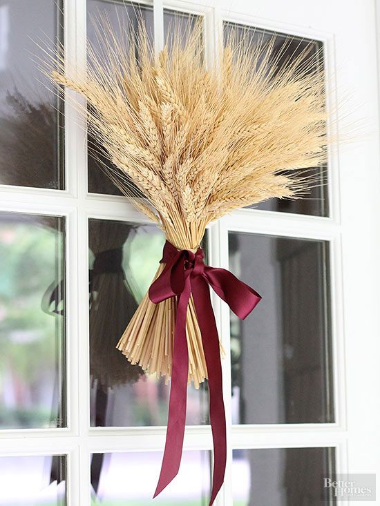 a wheat arrangement with a purple ribbon bow can be hung on your front door instead of a usual wreath to make it amazingly fall-like