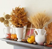 fall mantel decor with nuts, acorns, pumpkins, leathers and white vases and jugs with dried blooms and wheat is warm and cozy