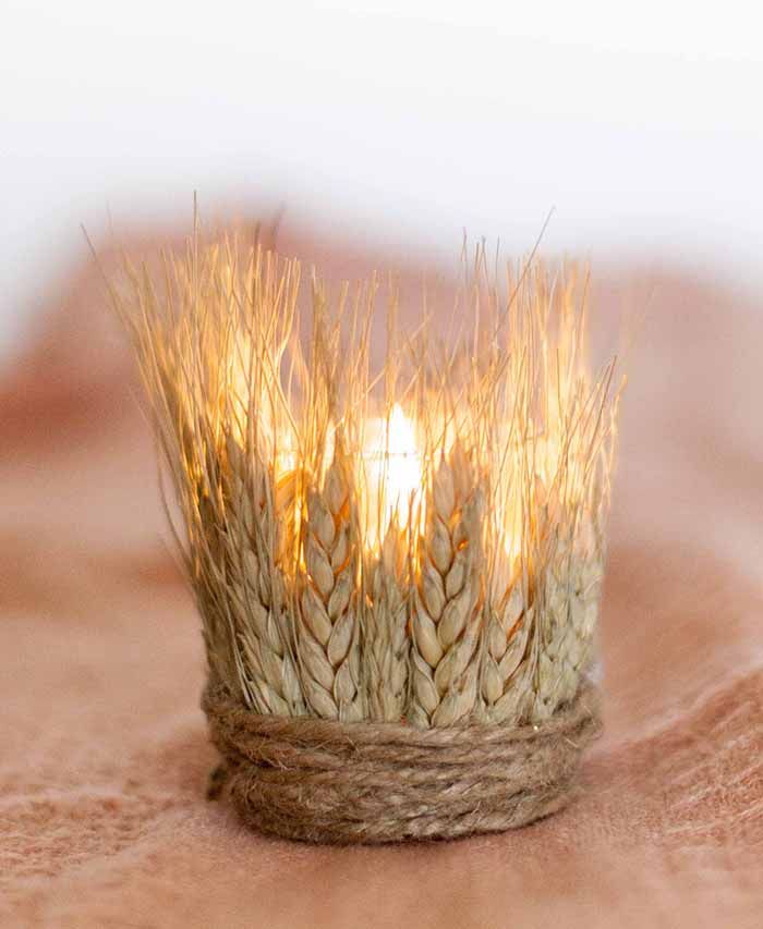 A glass candle holder covered with wheat and twine looks rustic and fall like