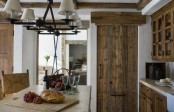 a reclaimed wood kitchen with a wooden table and stone countertops and a lamp hanging over the table