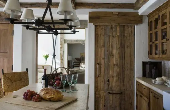 a reclaimed wood kitchen with a wooden table and stone countertops and a lamp hanging over the table