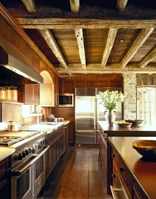 A cozy chalet kitchen all clad with wood, with wooden beams on the ceiling, with rustic and vintage furniture and built in lights