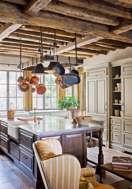 a neutral traditional kitchen with chalet touches - a wooden ceiling with beams, a dark stained kitchen island and pans hanging over the kitchen island