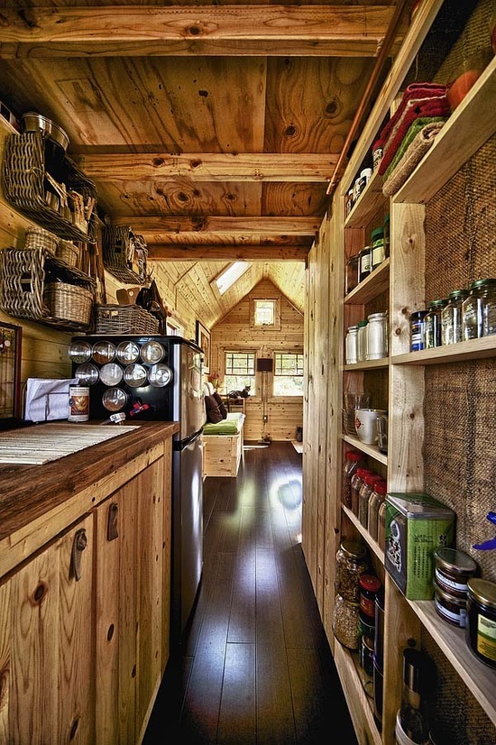 a small and narrow chalet kitchen with reclaimed wood, a burlap covered wall, wooden cabinets and a wooden ceiling with beams