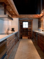 a reclaimed wood chalet kitchen with white stone countertops and built-in lights and metal handles looks unique