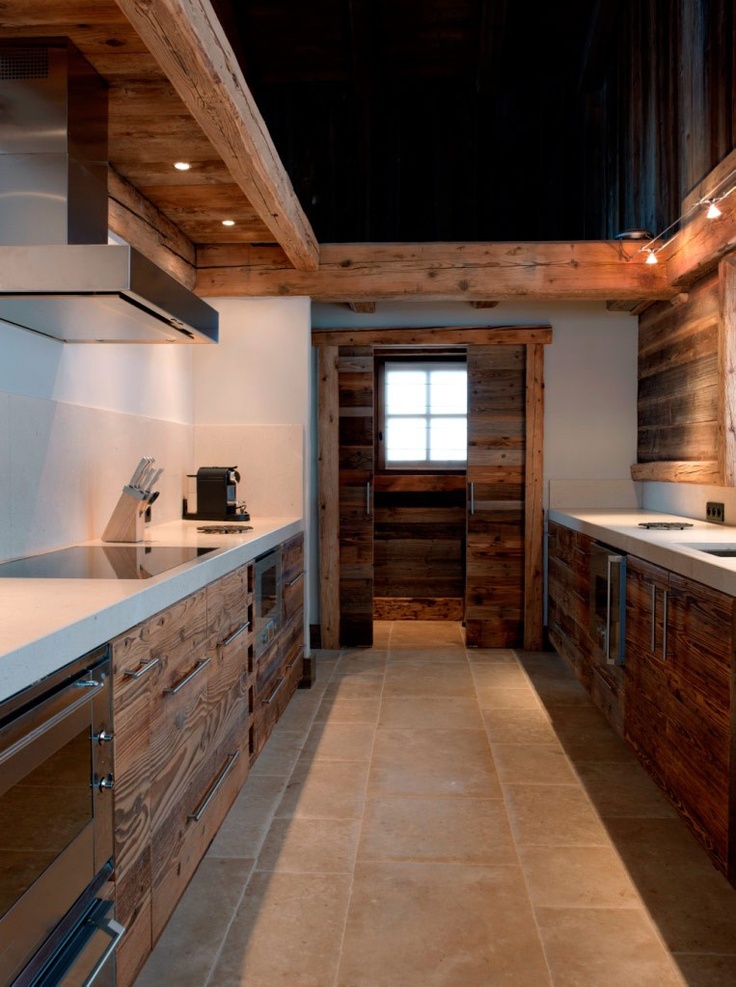 A reclaimed wood chalet kitchen with white stone countertops and built in lights and metal handles looks unique