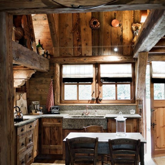 a cool chalet kitchen done with reclaimed wood, with wooden beams, stone countertops and some lights here and there