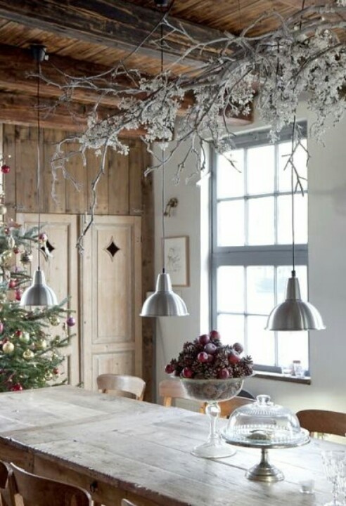 a Christmas tree, a frozen branch arrangement over the table and a Christmas centerpiece with apples and pinecones