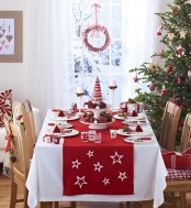 a Christmas tree with red and white ornaments, red and white runner, napkins and candles for a holiday feel