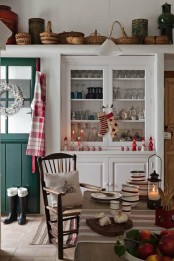 a plaid apron, red and white candles and accessories and printed stockings for a cozy holiday feel in the space
