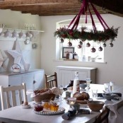 a Christmas chandelier with evergreens, purple ribbons and pastel ornaments over the table and a large white star