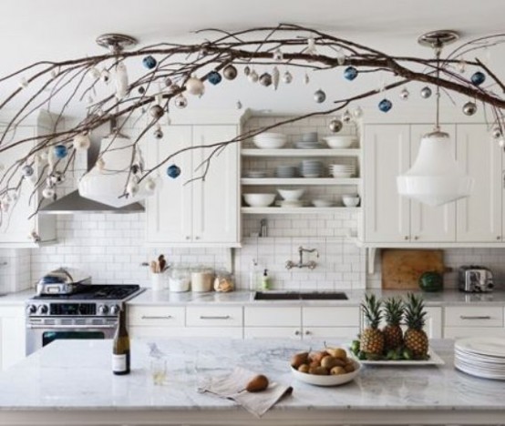 branches with white and blue ornaments over the kitchen island make the space feel holiday-like