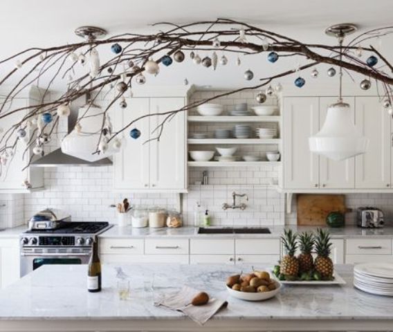 Branches with white and blue ornaments over the kitchen island make the space feel holiday like