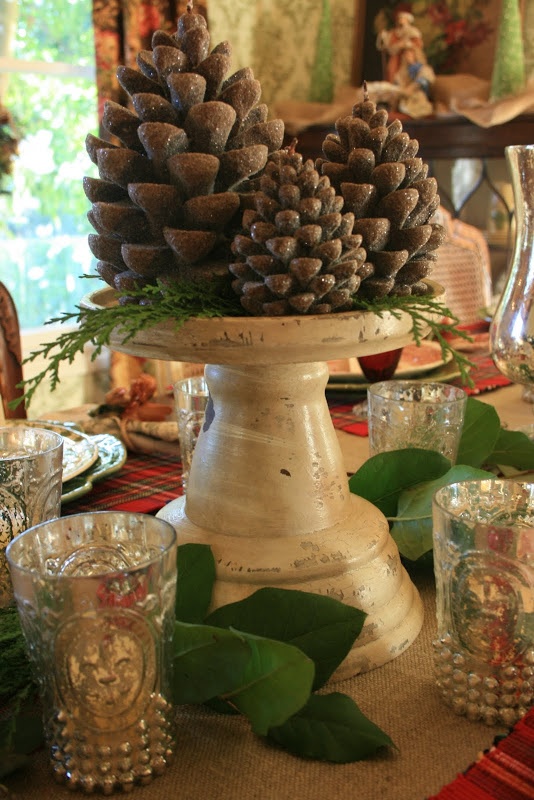 a vintage meets rustic centerpiece of a vintage stand and oversized glitter pinecones for a cool fall look