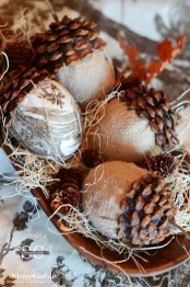 a whimsy wedding centerpiece of a wooden bowl with hay and pinecones made of burlap and usual pinecone parts
