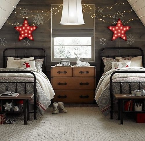 A grey reclaimed wood accent wall with red marquee stars, lights and red and grey Christmas themed bedding