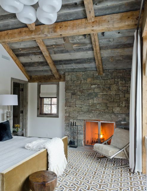 Simple furniture and textiles can balance out a texture heave interior that features such things as a weathered wooden ceiling and a stone fireplace.