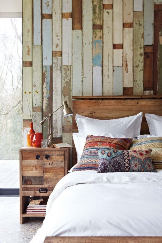 An accent wall covered with rough wood planks that show their paining history is a perfect addition to a rustic bedroom.
