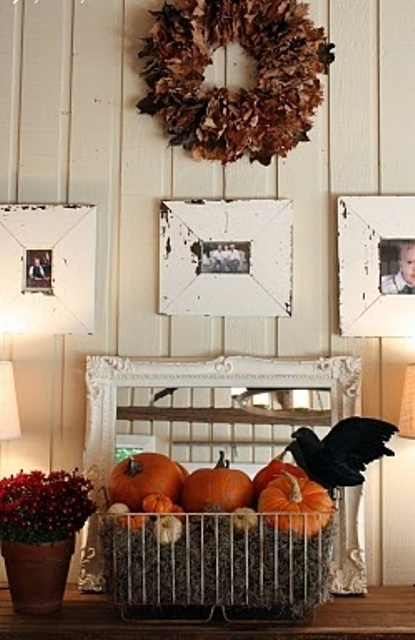 a dried leaf and dark bloom wreath, a wire basket with hay, pumpkins and a crow for styling your space for Halloween