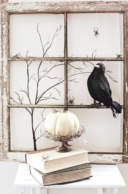 a shabby chic window frame, a crow, branches and a pumpkin on a stand with hay is stylish for a rustic Halloween space