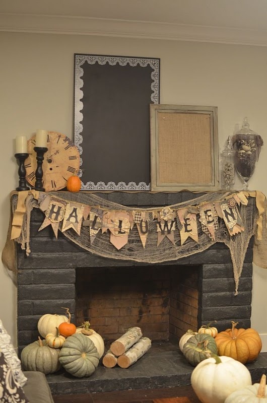 a rustic Halloween fireplace with a burlap and cheesecloth banner, heirlloom pumpkins and firewood around it