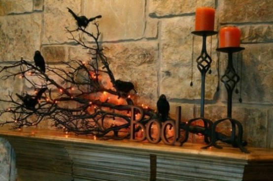 rustic Halloween mantel styling with scary branches, blackbirds, candles and lights and orange candles is very chic