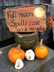 a wooden rustic sign and pumpkins and ghosts for styling your space for Halloween with rustic touches