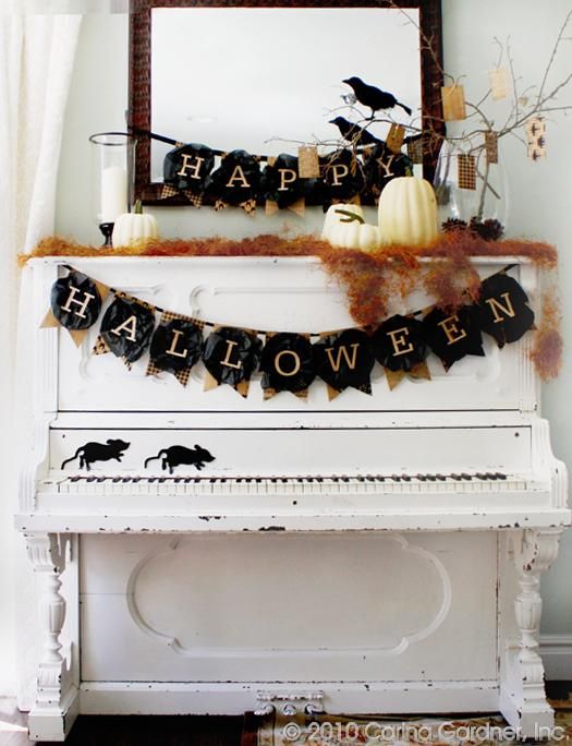 rustic Halloween decor with burlap and black fabric banners, orange hay, crows, branches and white pumpkins