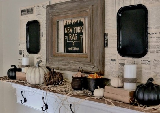 a rustic Halloween mantel with hay, black and white pumpkins, candles, cauldrons with candies and black trays