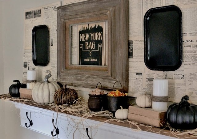 A rustic Halloween mantel with hay, black and white pumpkins, candles, cauldrons with candies and black trays