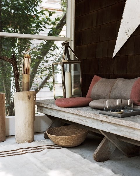 a rustic space with a wooden bench, with a basket, a candle lantern and a concrete container
